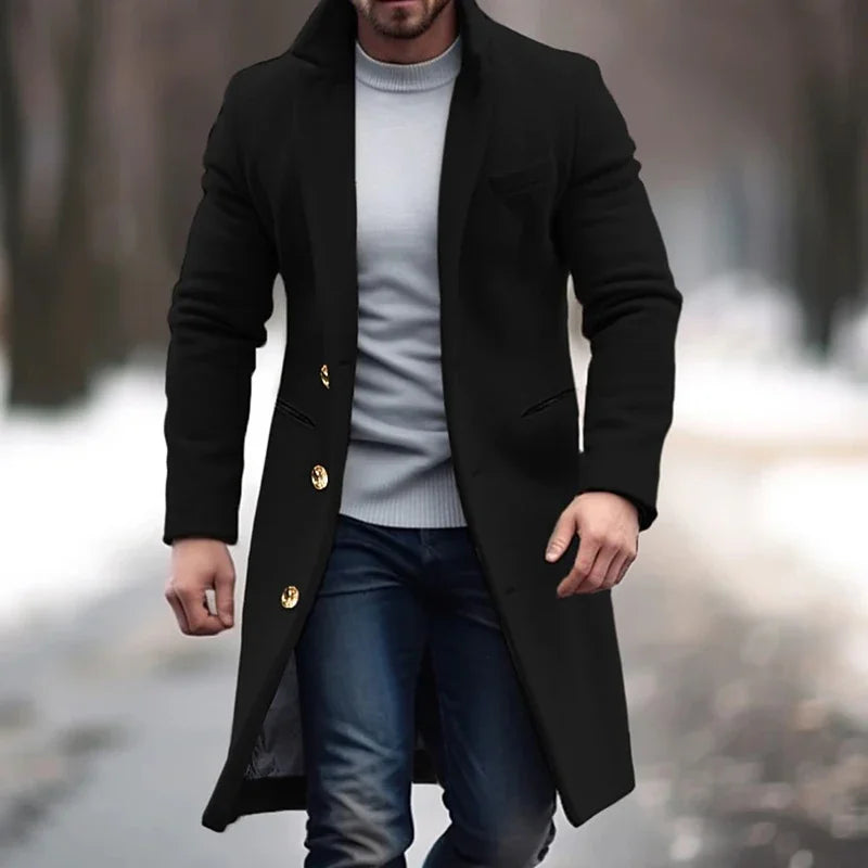 Cappotto uomo nero elegante, lungo, con bottoni dorati, indossato su maglione grigio e jeans. Moda invernale maschile, stile casual chic.