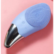 Spazzola viso elettrica in silicone blu su sfondo rosa, con pulsanti di controllo e base in metallo. Dispositivo per pulizia e cura della pelle.