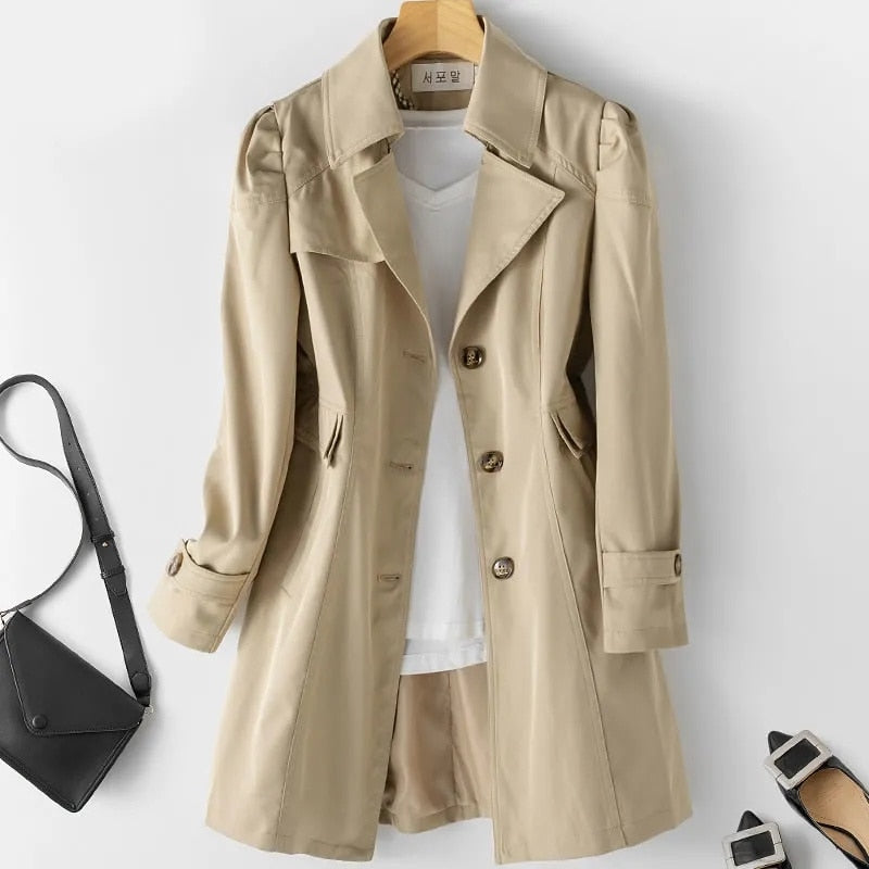 Cappotto beige da donna elegante, con bottoni e tasche, abbinato a maglietta bianca e borsa nera. Moda autunnale, abbigliamento casual chic.