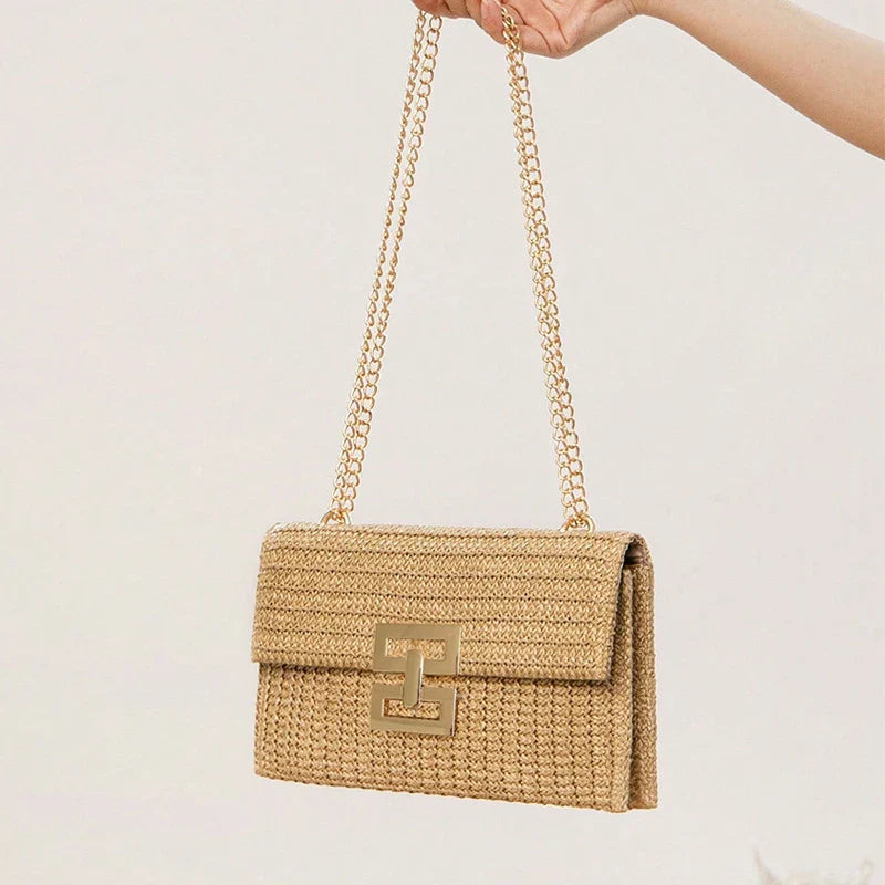 Borsa a tracolla in paglia beige con catena dorata, chiusura decorativa, design elegante e moderno. Accessorio moda estivo per donna.