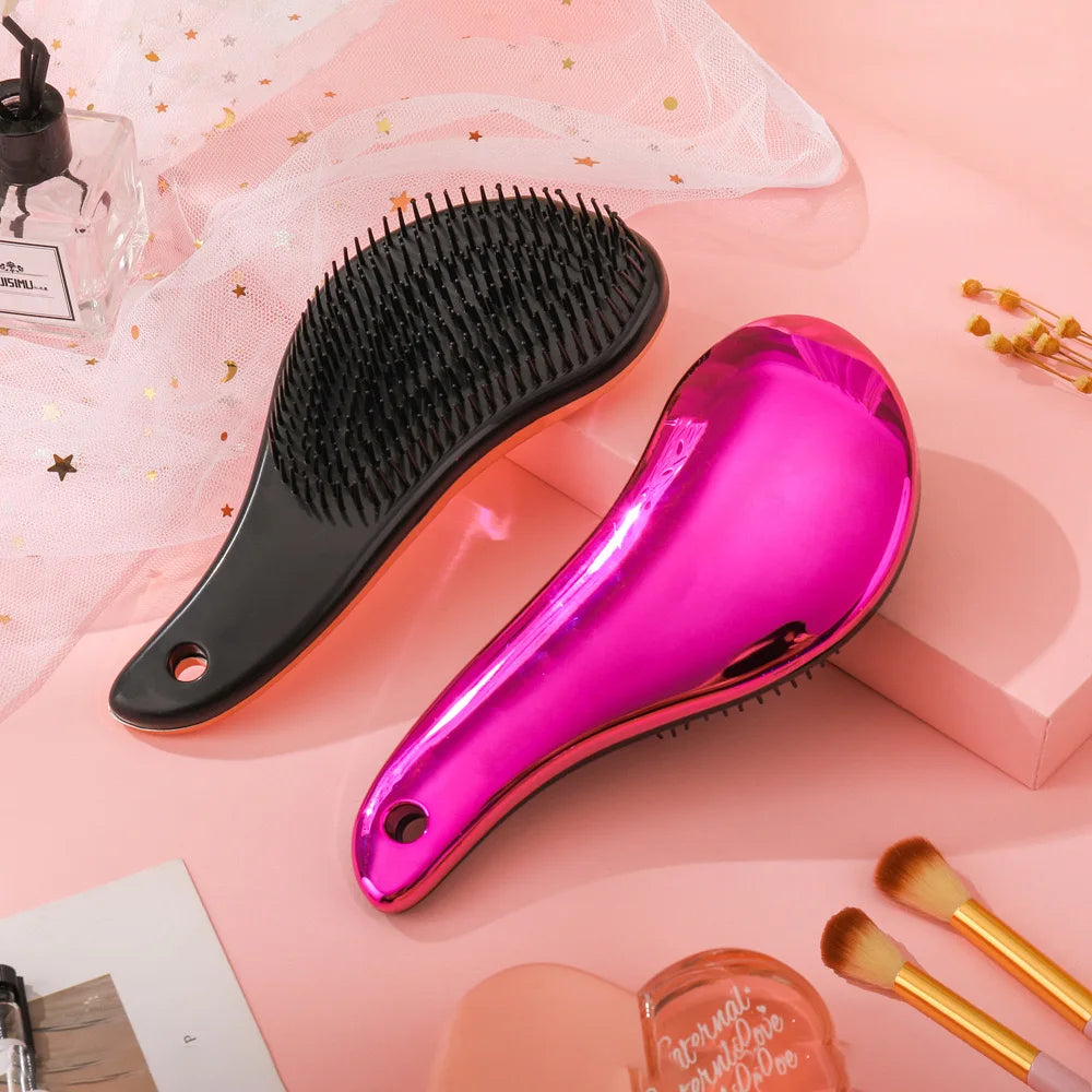 Spazzole districanti per capelli, una nera e una rosa metallizzata, su sfondo rosa con accessori di bellezza. Ideali per capelli lisci e ricci.