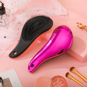 Spazzole districanti per capelli, una nera e una rosa metallizzata, su sfondo rosa con accessori di bellezza. Ideali per capelli lisci e ricci.