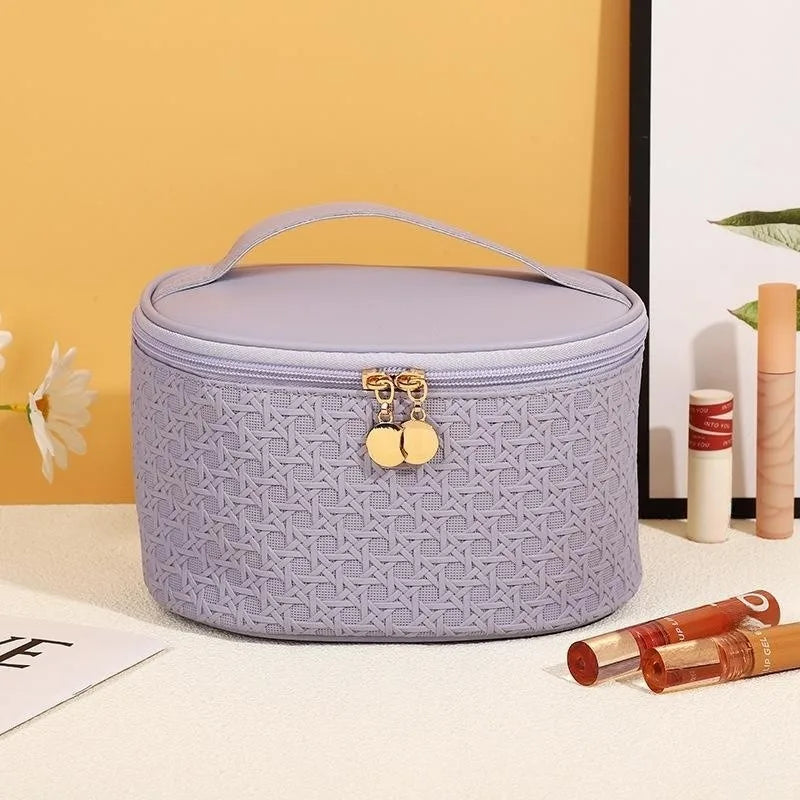 Astuccio cosmetico viola con motivo intrecciato, chiusura a zip dorata, manico superiore. Ideale per trucco, accessori viaggio, organizer bellezza.