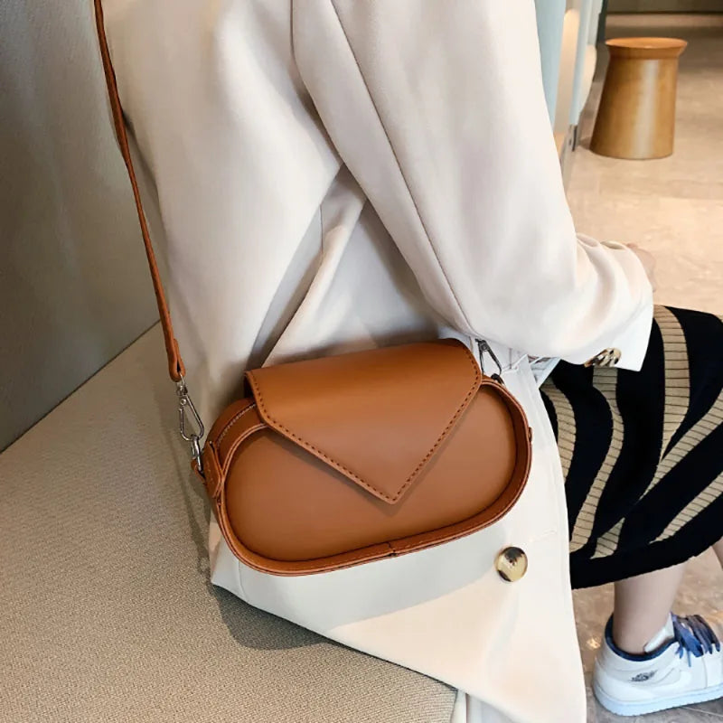Borsa a tracolla in pelle marrone su giacca beige, design elegante e moderno, accessorio moda donna, perfetta per look casual e formali.