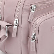 Zaino rosa in tessuto resistente con cerniere multiple e dettagli in metallo argentato, ideale per moda femminile e viaggi.