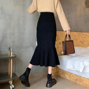 Donna con maglione beige e gonna nera a sirena, stivali neri, borsa marrone. Moda autunnale elegante, abbigliamento casual chic.