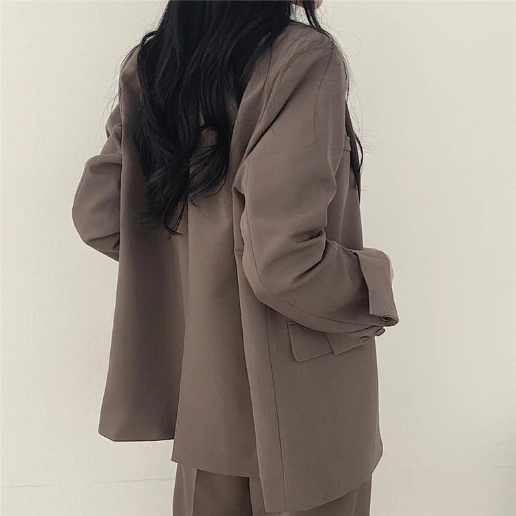 Donna con giacca oversize beige, capelli lunghi neri, stile minimalista. Moda autunnale, abbigliamento casual elegante, tendenze 2023.