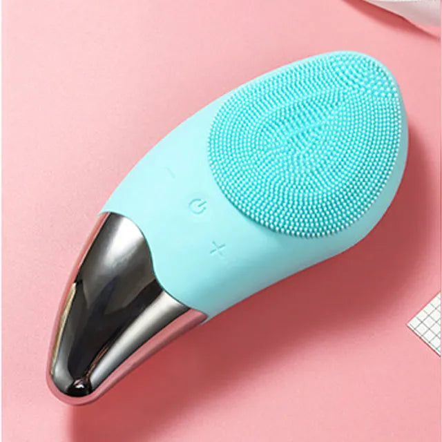 Dispositivo di pulizia viso in silicone blu, massaggiatore elettrico con testina in acciaio inossidabile, su sfondo rosa.