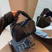 Borsa a mano nera in tessuto con manico arricciato, zip argentate, riflessa in uno specchio. Design moderno, accessorio moda elegante.