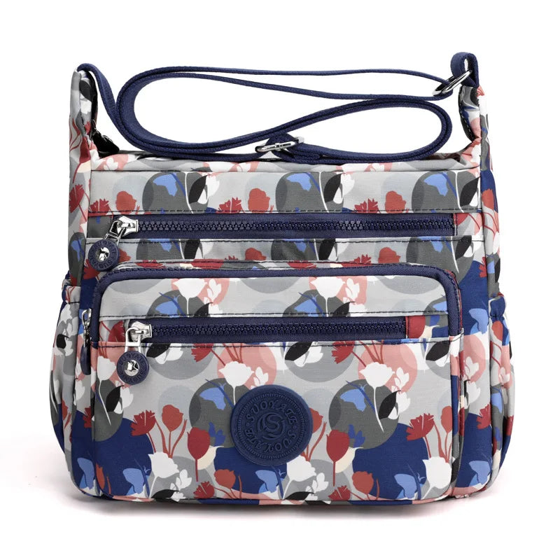 Borsa a tracolla floreale multicolore con tasche multiple e cerniere, design moderno e pratico, ideale per uso quotidiano e viaggi.