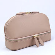 Elegante borsa cosmetica in pelle beige con doppia cerniera dorata, design compatto e moderno. Accessorio ideale per organizzare trucchi e cosmetici.