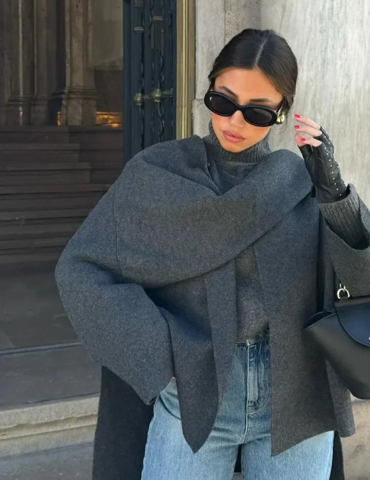 Donna con occhiali da sole, cappotto grigio elegante, guanti in pelle nera e jeans, moda autunnale, stile urbano sofisticato.