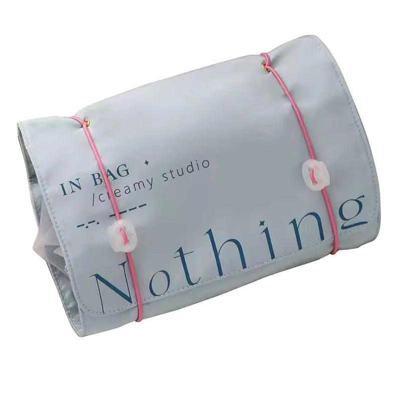 Borsa organizer da viaggio grigia con scritta "Nothing", chiusura con elastici rosa. Ideale per cosmetici, accessori, articoli da toeletta.
