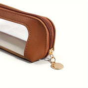 Astuccio trasparente in pelle marrone con cerniera dorata e portachiavi. Design elegante e funzionale per scuola o ufficio.
