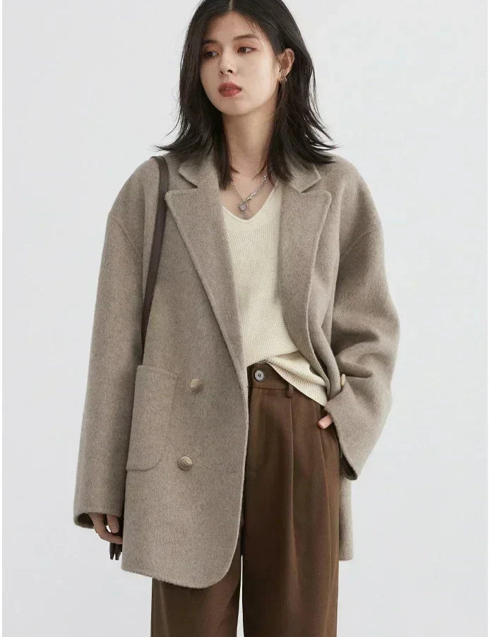 Donna con cappotto oversize beige, maglione crema e pantaloni marroni. Moda autunnale, abbigliamento casual elegante, stile minimalista.
