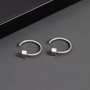 Orecchini a cerchio in argento con design minimalista e cubo geometrico, eleganti e moderni, ideali per moda donna e accessori gioielli.