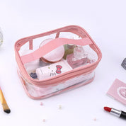 Borsa trasparente da trucco rosa con cerniera, contenente cosmetici vari come rossetto, crema e profumo. Ideale per organizzare il make-up.