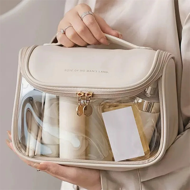 Borsa trasparente da viaggio in PVC beige, con cerniera e manico, contenente flaconi e accessori. Ideale per cosmetici e articoli da toeletta.