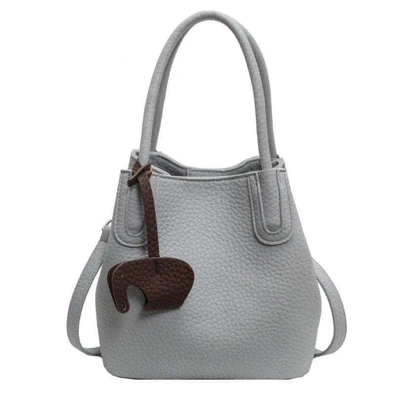 Borsa a mano in pelle grigia con ciondolo elefante marrone, design elegante, manici doppi, tracolla regolabile. Accessorio moda donna.
