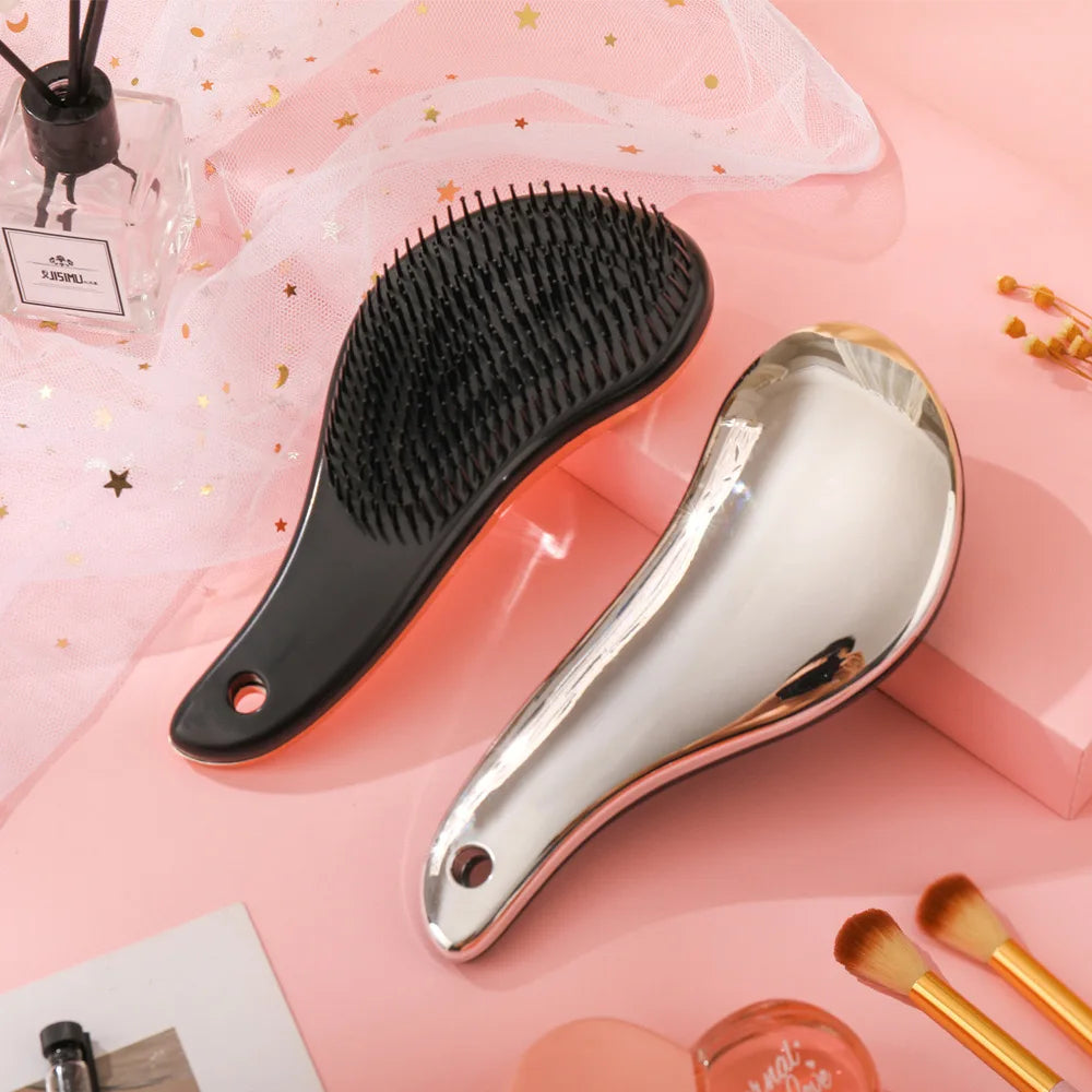 Spazzola per capelli nera e argento su sfondo rosa, design ergonomico, setole morbide, ideale per districare e lisciare, accessorio bellezza.