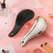Spazzola per capelli nera e argento su sfondo rosa, design ergonomico, setole morbide, ideale per districare e lisciare, accessorio bellezza.