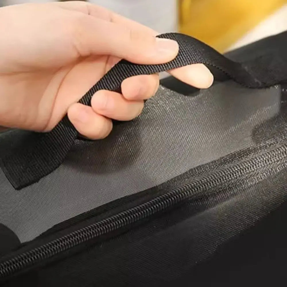 Mano che tiene una maniglia di una borsa in tessuto nero, chiusura lampo visibile. Borsa resistente, ideale per viaggi e trasporti.