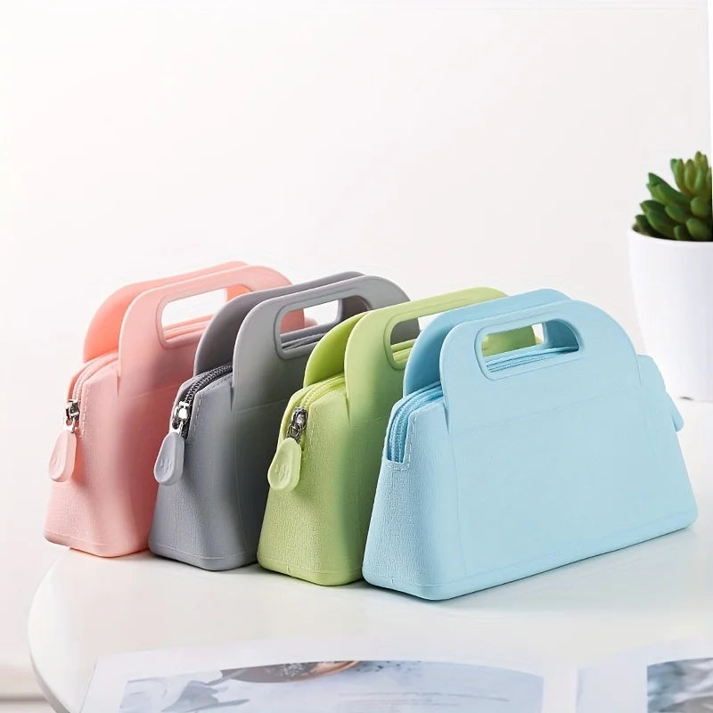 Quattro borse termiche colorate in silicone su tavolo bianco, colori pastello: rosa, grigio, verde, azzurro. Design moderno, chiusura a zip.