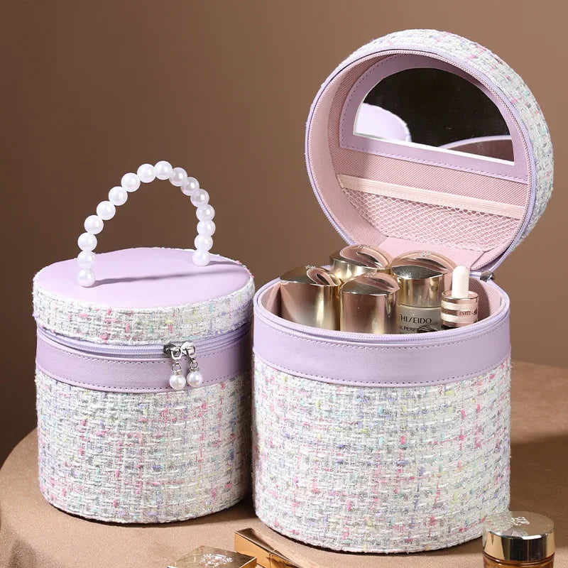 Scatola porta trucchi rotonda in tessuto tweed lilla con manico di perle, specchio interno e cerniera, ideale per cosmetici e accessori da viaggio.