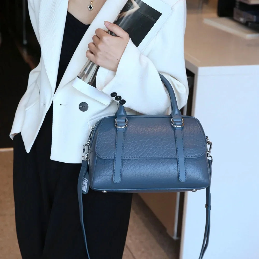 Donna con borsa a mano in pelle blu, elegante e moderna, indossa blazer bianco. Accessorio moda femminile, stile casual chic.