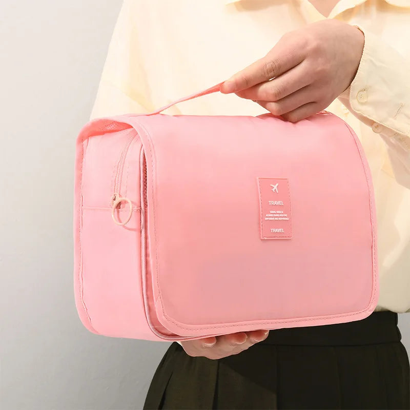Borsa da viaggio rosa, compatta e portatile, con manico. Ideale per organizzare accessori e cosmetici. Design elegante e funzionale.