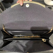 Elegante borsa a tracolla nera aperta, con catena dorata e chiusura magnetica. Design interno con scomparti multipli e dettagli raffinati.