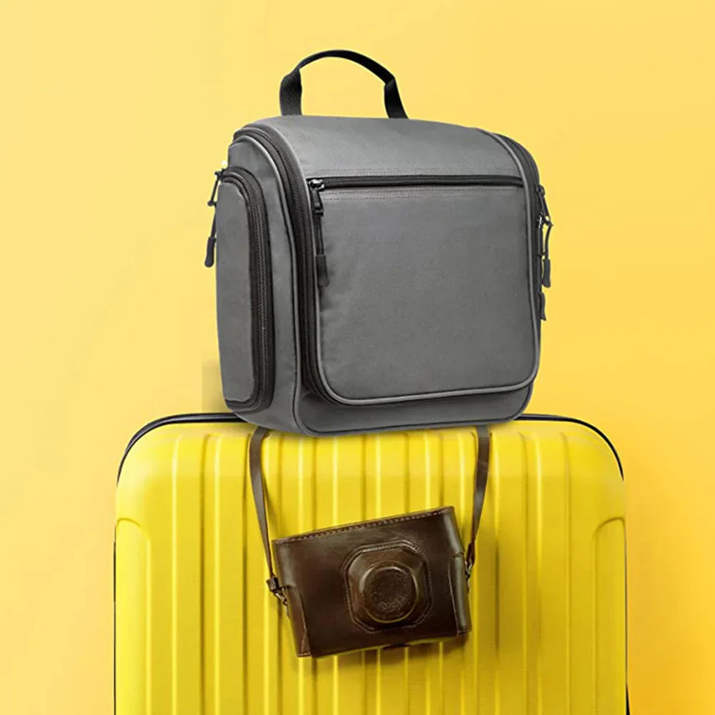 Borsa da viaggio grigia su valigia gialla con borsa a tracolla marrone, sfondo giallo. Accessori viaggio eleganti e funzionali.