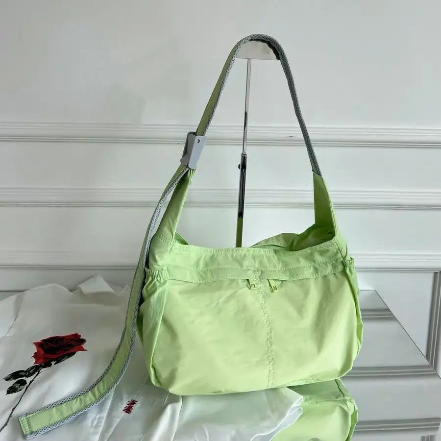 Borsa a tracolla verde chiaro su sfondo bianco, design moderno, tessuto leggero, ideale per moda casual e quotidiana. Accessorio femminile elegante.