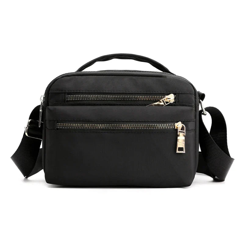 Borsa a tracolla nera in nylon con doppia cerniera, manico superiore e tracolla regolabile. Design elegante e pratico per uso quotidiano.