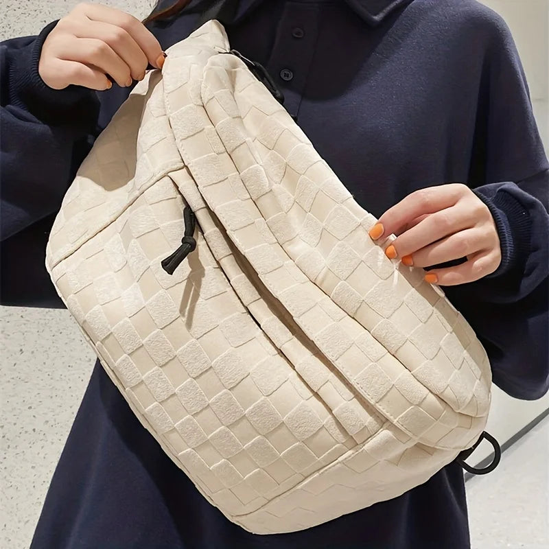 Borsa a tracolla beige intrecciata, indossata da una persona con maglia blu scuro. Design elegante e moderno, ideale per moda urbana e casual.