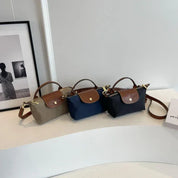 Tre borse a tracolla eleganti in tessuto e pelle, colori beige, blu e nero, su tavolo bianco. Design moderno, accessori moda donna.