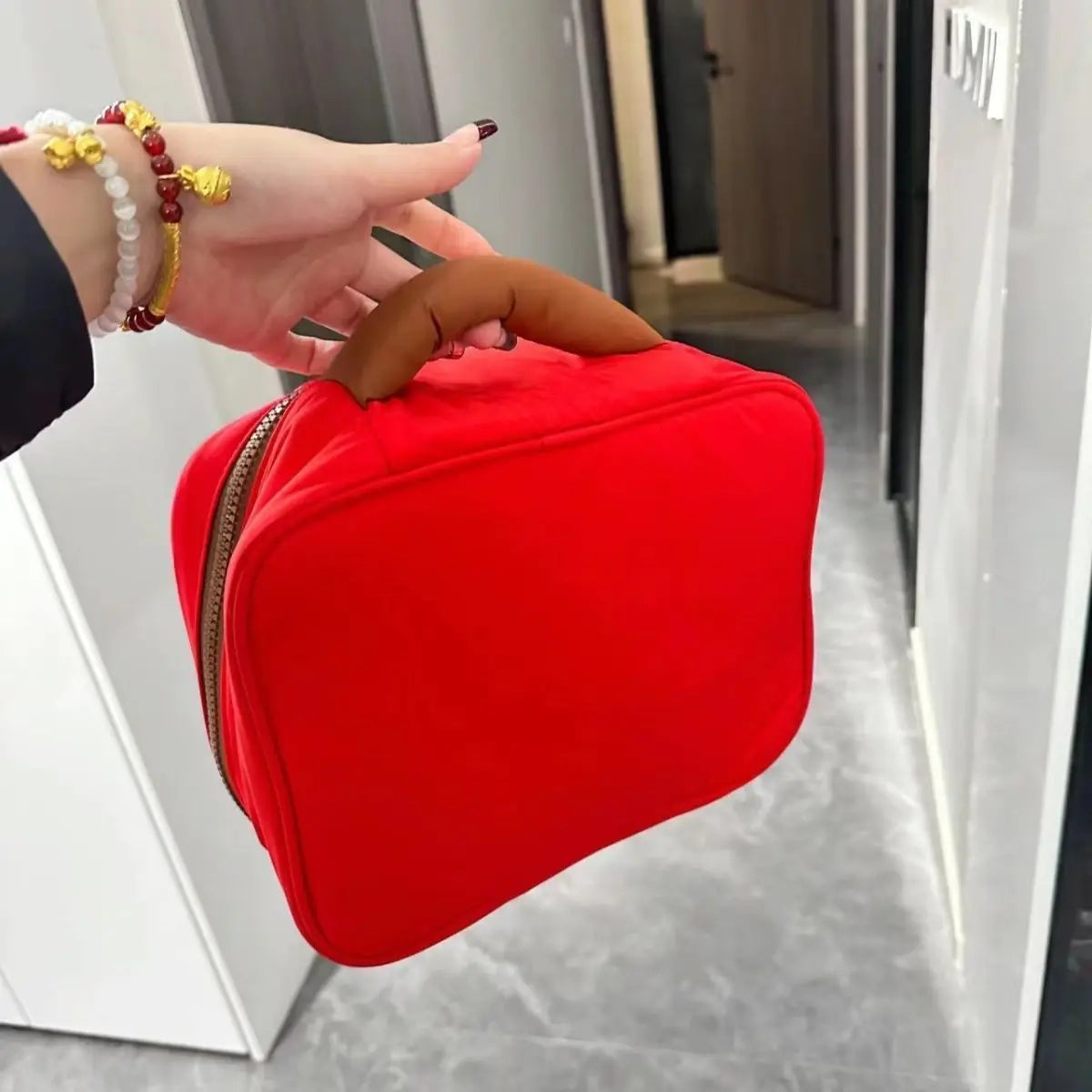 Borsa termica rossa con manico marrone, chiusura a zip, ideale per pranzo al sacco. Design compatto, perfetta per ufficio o scuola.