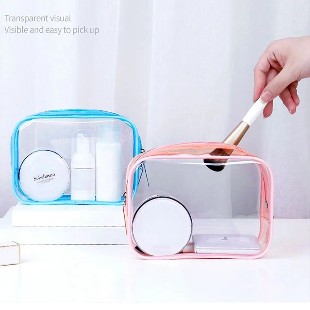 Due astucci trasparenti per cosmetici, uno blu e uno rosa, con prodotti di bellezza e pennello. Design pratico, ideale per viaggio e organizzazione.