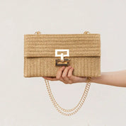 Borsa a tracolla in paglia beige con chiusura dorata e catena, design elegante e moderno, perfetta per l'estate. Accessorio moda donna.