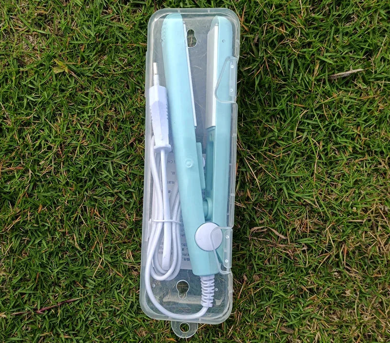 Piastra per capelli portatile verde menta in custodia trasparente su erba. Include cavo di alimentazione. Ideale per styling capelli in viaggio.