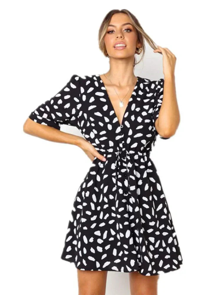 Abito corto nero a pois bianchi, scollo a V, maniche corte, stile casual elegante, perfetto per moda donna estate.