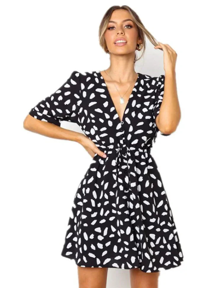 Abito corto nero a pois bianchi, scollo a V, maniche corte, stile casual elegante, perfetto per moda donna estate.