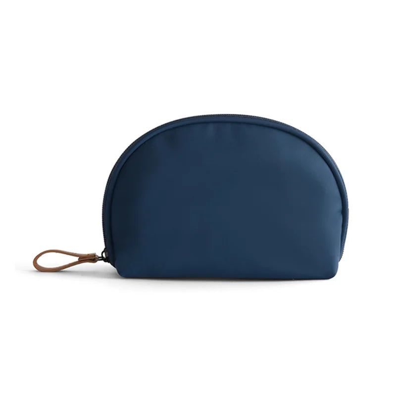 Astuccio cosmetico blu navy in tessuto impermeabile con cerniera e manico in pelle marrone. Ideale per viaggio, organizzazione trucco.