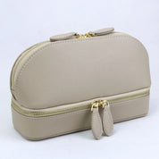 Elegante borsa cosmetica in pelle beige con doppia cerniera dorata, design compatto e moderno, ideale per organizzare trucchi e accessori da viaggio.