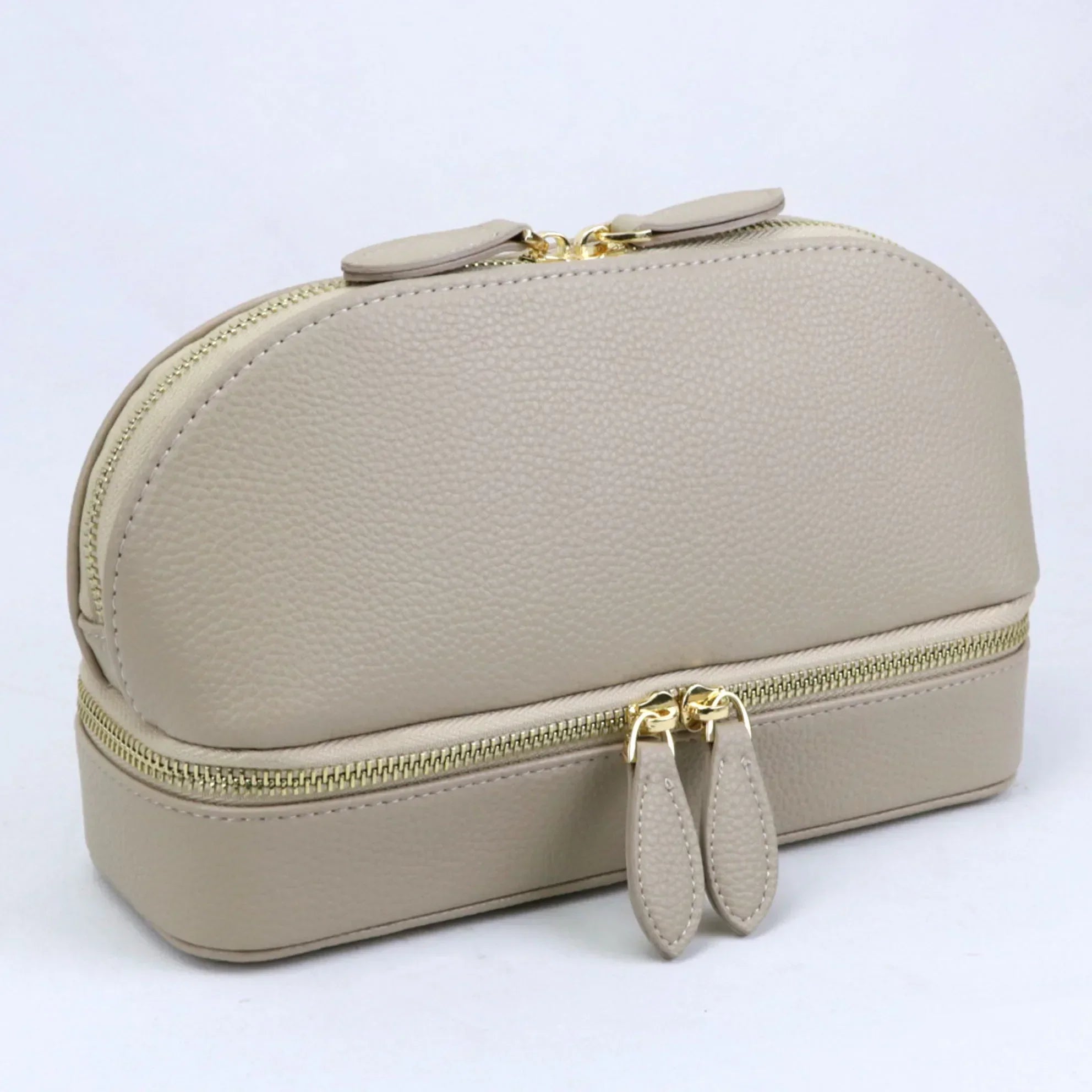 Elegante borsa cosmetica in pelle beige con doppia cerniera dorata, design compatto e moderno, ideale per organizzare trucchi e accessori da viaggio.