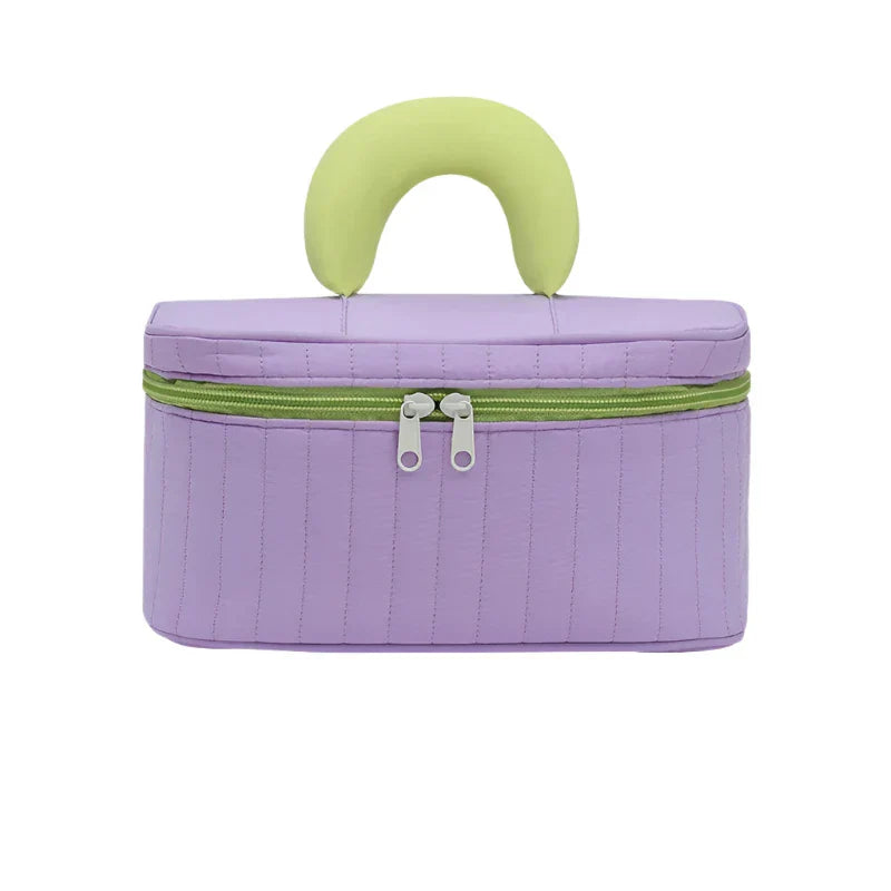 Borsa cosmetica viola con manico verde, chiusura a zip, design moderno. Ideale per viaggi, organizzazione trucco, accessori beauty.