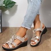 Sandali donna con zeppa, color oro, decorati con fiori, indossati con jeans chiari. Scarpe estive eleganti, comode e alla moda.