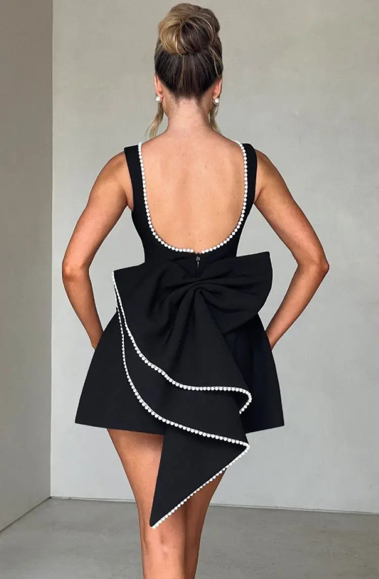 Abito nero elegante con fiocco posteriore e dettagli perle, design senza maniche, scollatura profonda, moda donna, abbigliamento da sera sofisticato.