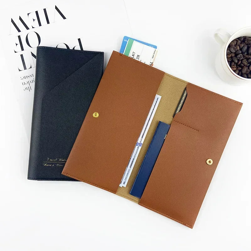 Portadocumenti in pelle marrone e nero su scrivania bianca, con tazza di caffè e rivista. Elegante organizer per ufficio, ideale per viaggi d'affari.