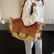 Donna con borsa a tracolla in tela e pelle marrone, stile casual. Accessorio moda versatile per uso quotidiano. Design moderno e funzionale.